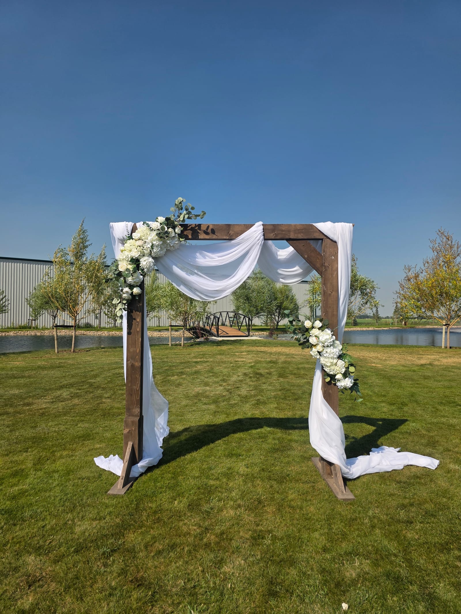 Outdoor ceremony arch beside the pond at The Byre in Coaldale Alberta