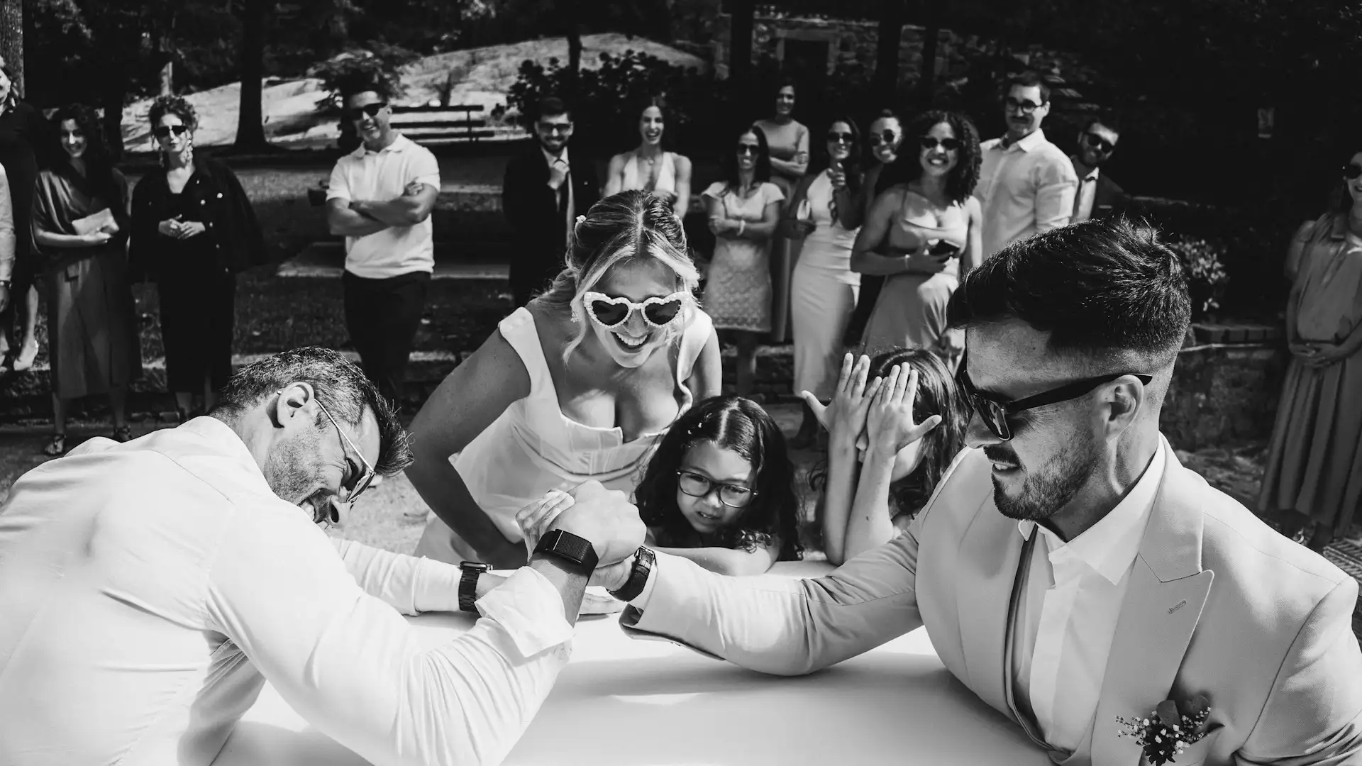 Wedding guests arm wrestling while bride and groom cheer them on