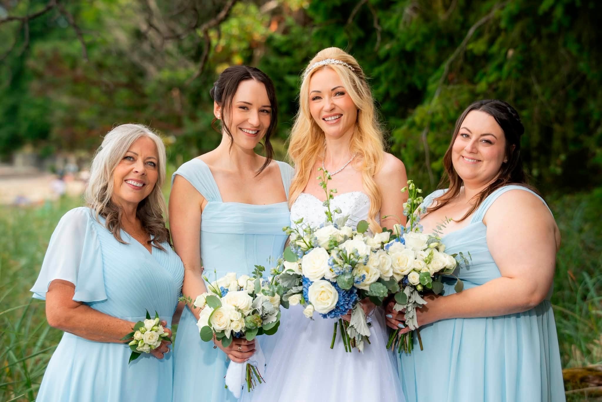 Charlene with women from the wedding party in pale blue dresses, all holding white and blue bouquets