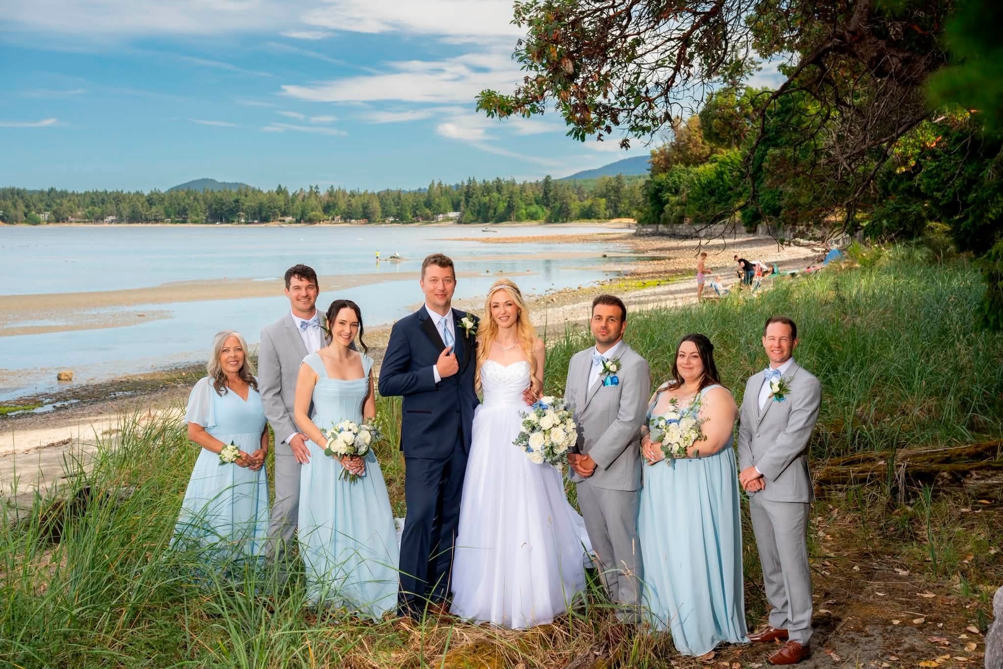 The wedding party lined up on the beach in Parksville with the ocean behind them