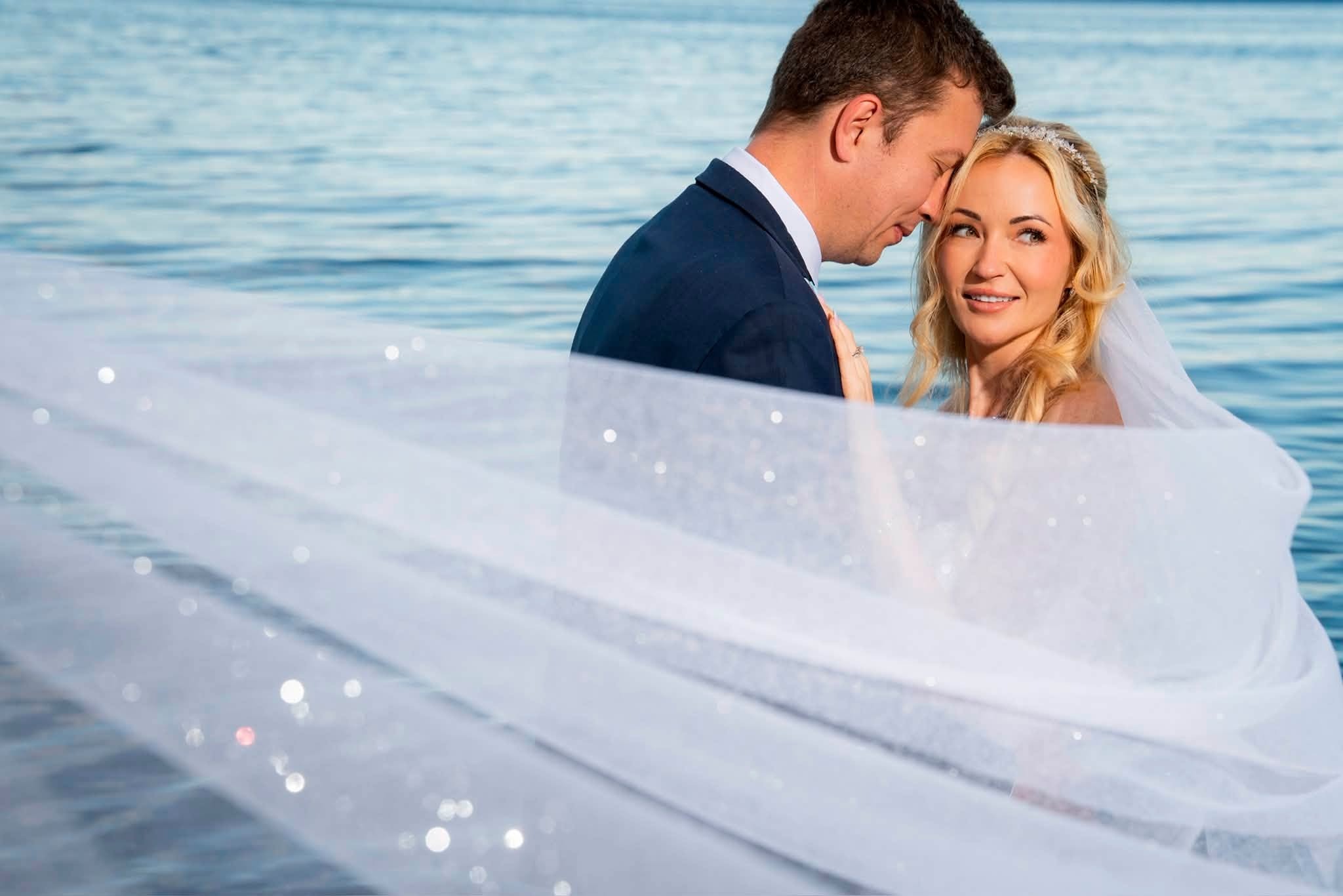Charlene's sparkly veil sweeping across the frame as the couple stands by the ocean in Parksville