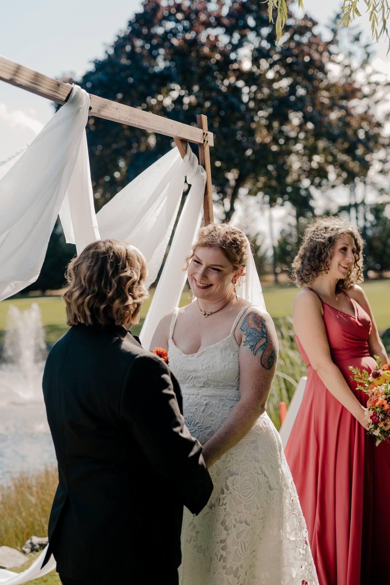 Deavon smiling during the vows under a draped wooden arbour