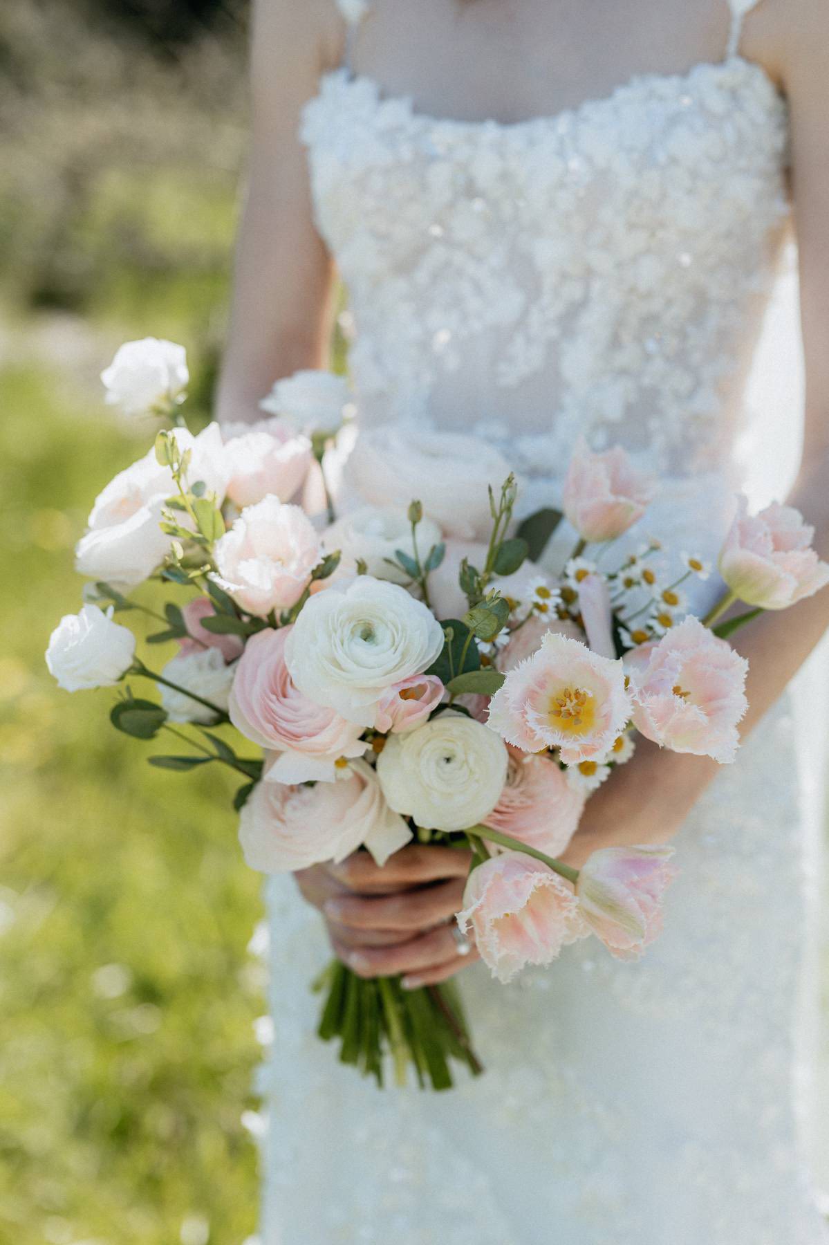 Bridal bouquet of pink and white ranunculus, lisianthus, and tulips