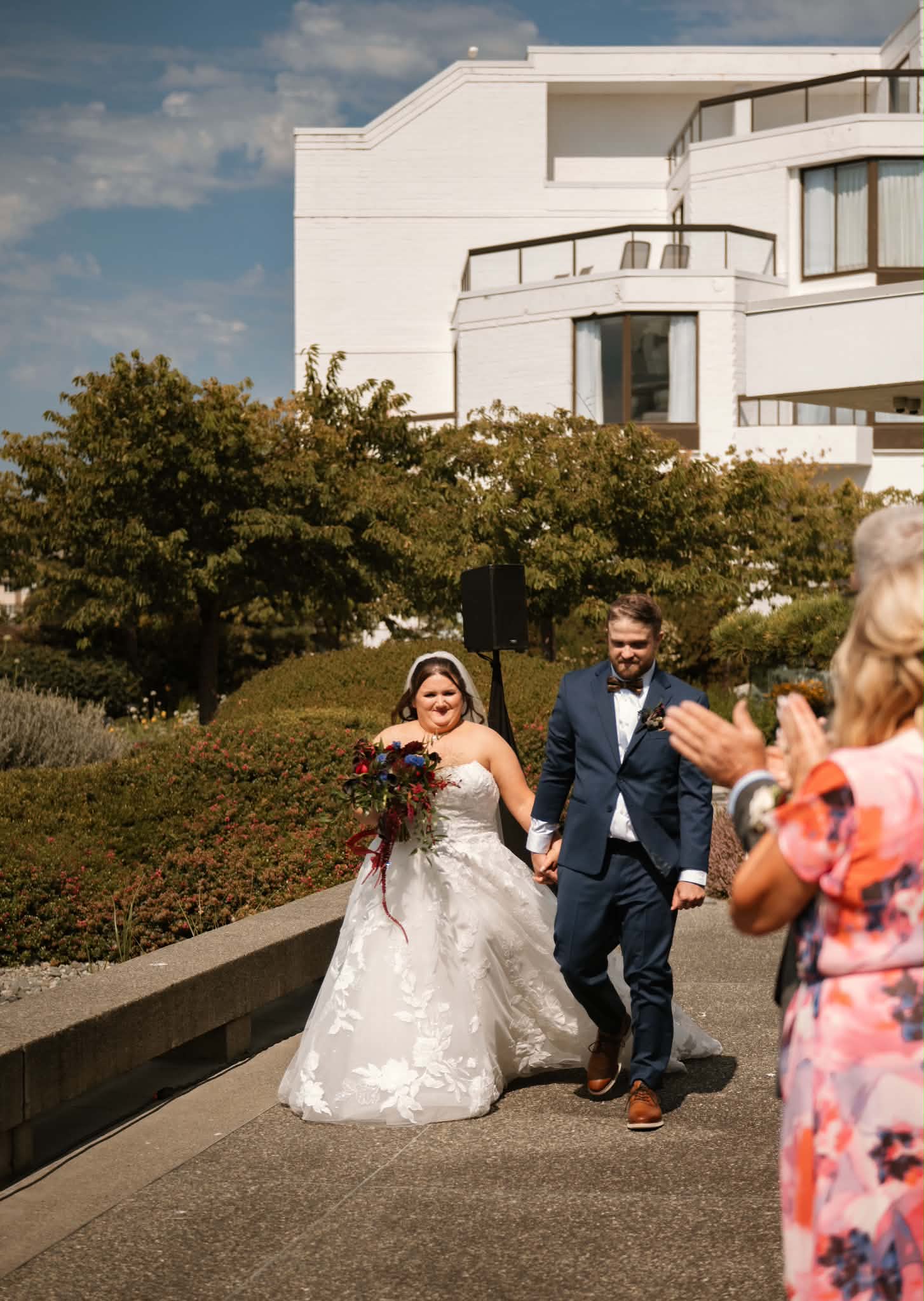 Emily and Sheldon walking back up the aisle as guests clap